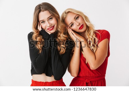 Image of a happy young two girls friends posing isolated over white wall dressed in black and red clothes.