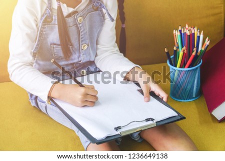 Cute little girl drawing picture with color pencils on the paper, Childhood development and learning concept.