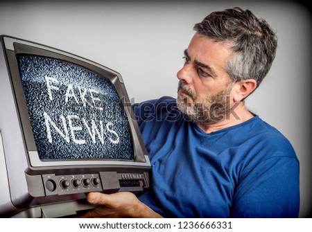 Middle-aged man holds a TV with fake news screen, conceptual image