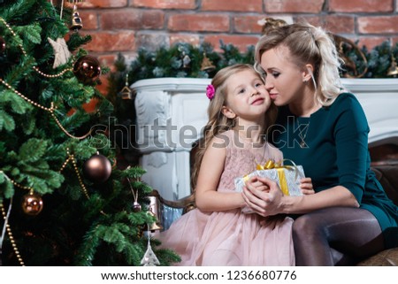 Mom gives a Christmas gift to her daughter, and she kisses her.