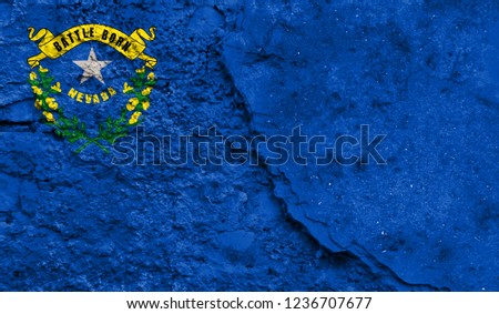 Flag State of Nevada close up painted on a cracked wall, concept of armed actions and conflicts in the world
