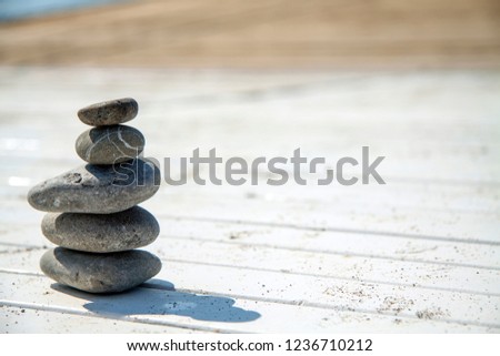 round spa sea stones, pebbles, pyramid on a light wooden background, seashore