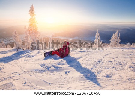 Young woman on snowboard sits snow and waits for instructor to skate freely. Sheregesh Ski Resort