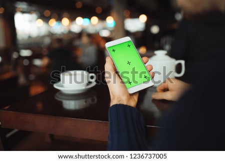 Green screen of smartphone, hand holding digital display in cafe background
