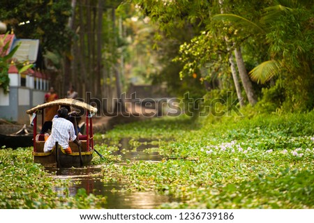 Some tourists are on a canoe sailing on the lush and green backwaters in Alleppey during the sunset, Kerala, India. Alleppey is one of the famous backwater tour destinations in Kerala. Royalty-Free Stock Photo #1236739186