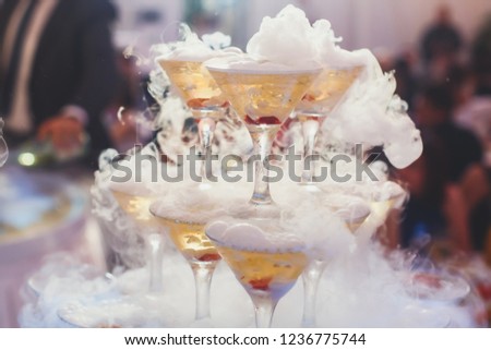 Beautiful pyramid line of different colored alcohol cocktails with mint on a open air party, tequila, martini, vodka, and others on decorated catering bouquet table on open air event
