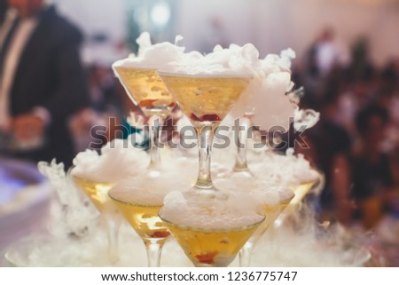 Beautiful pyramid line of different colored alcohol cocktails with mint on a open air party, tequila, martini, vodka, and others on decorated catering bouquet table on open air event
