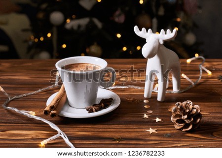 Vintage photo, spices, hot coffee in white cup and christmas tree with lights in background
