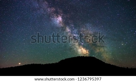 Colorful vibrant milkyway galaxy with stars and space dust in the universe above the dark hill on night sky