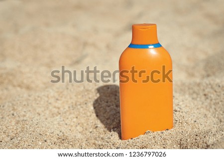 Summer holidays. Sunscreen protection cream is laying in the sand near the sea.