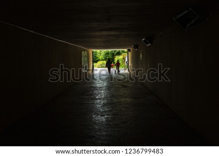 Long stone tunnel. Light at the end of the tunnel at the destination. Silhouettes in a tunnel against the background of light at the end of the road. Gloomy creepy picture as background for design.