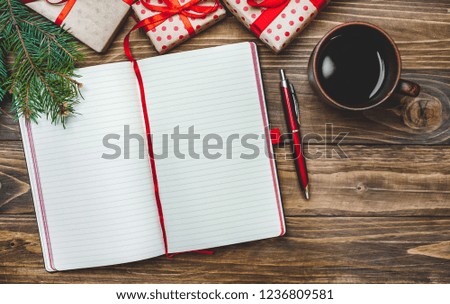 Planning a new year. Laptop to make a list near Christmas gifts, a fir branch and a cup of coffee on a wooden background