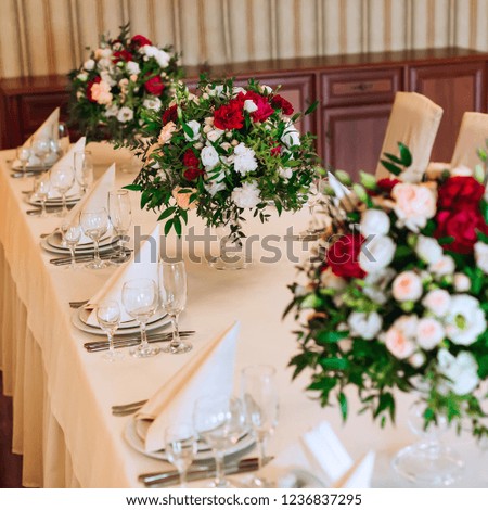 a close-up of a table with a white tablecloth on which cutlery, plates with napkins and glasses. beautiful bouquets in transparent vases