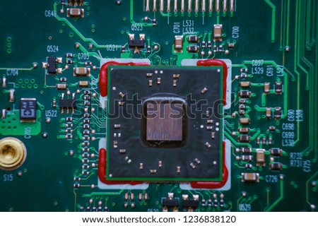Glowing modern processor. Big illuminated graphic processor surrounding by other electrical components. Special tone image. Low aperture shot, focus on lower part of chip. Macro photo