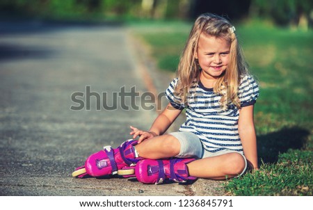Childhood time. Cute little girl learning to roller skates in the park