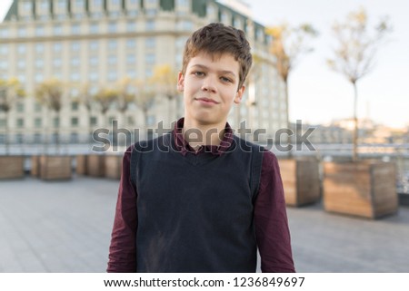 Outdoor portrait of smiling teenager boy 14, 15 years old. City background, golden hour Royalty-Free Stock Photo #1236849697