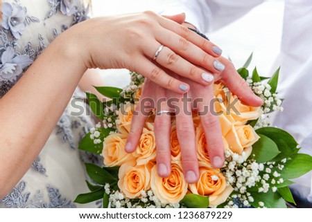 Bride and groom hands with wedding rings against background of bridal bouquet of flowers. Declaration of love, spring. Wedding card, Valentine's Day greeting. Wedding rings. Wedding day details