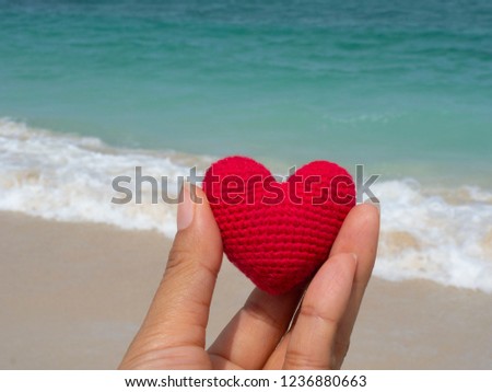 Hand are hold Red heart in the morning beside the beach replace the love in Valentine give heard. 