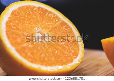 Close up picture of a juicy orange fruit in dark background on an old rustic wooden board