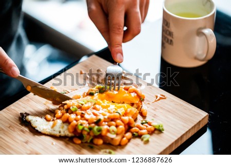 close up picture of breakfast. Tost, egg, beans, chives, on a wooden board, on a table. eating breakfast