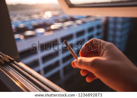 close up picture of a hand holing a cigarete. smoking, in urband background