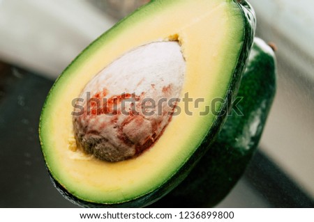 halved avocado with seed on mirror plate