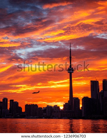 TORONTO CITY SKYLINE AT SUNSET - Amazing sunset scene of Toronto cityscape with dramatic colors and airplane flying by. Rare sky with intense, gorgeous colors and clouds. Toronto, Ontario, Canada