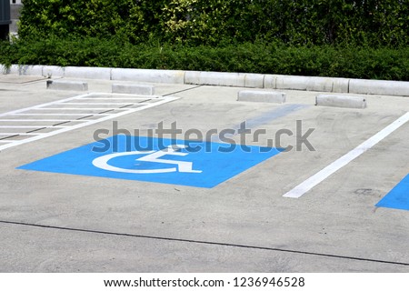 Designated parking space for people with disablities with blue and white painted on concrete floor at community mall.