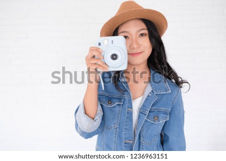 Beautiful girl wear jackets jeans and hat taking photo with blue camera.
