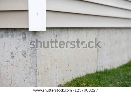 Grey or tan vinyl siding on a building with concrete foundation
