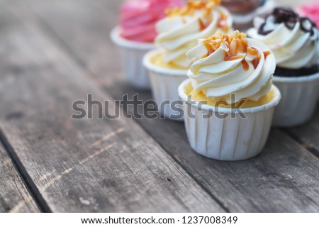 Group of fancy cup cakes, chocolate, caramel and strawberry on wooden table, birthday celebration concept, copy space