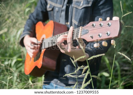 The man hold guitar In nature.