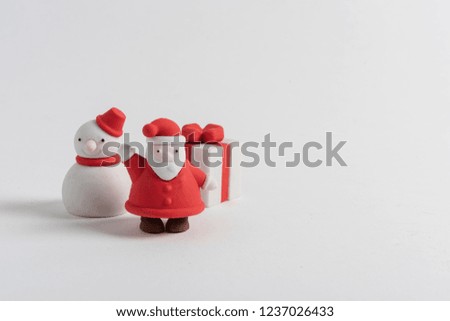 Miniature snowman, gift and santa claus figures with friendly pose with hat and red coat on white background. Merry Christmas