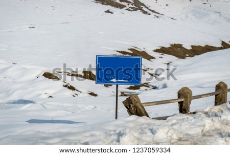 A blue sign board copy space board in a white snow landscape