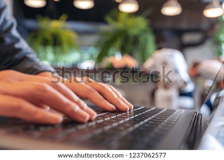 Closeup image of hands using and typing on laptop keyboard in cafe