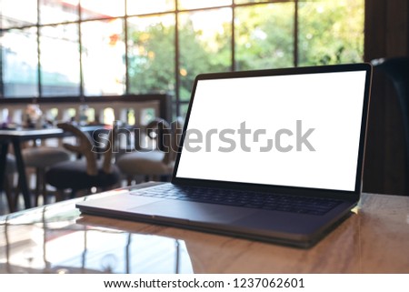Mockup image of laptop with blank white desktop screen on table in cafe
