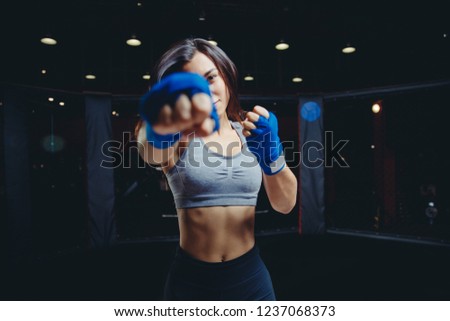 Punch fist to camera. Young girl is active in feminist movement boxing ring, hands blue protective bandages for MMA