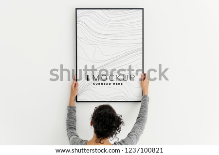 Woman putting up an art piece mockup at home Royalty-Free Stock Photo #1237100821