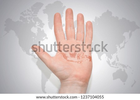 hand with map of indonesia on the gray world map background. concept