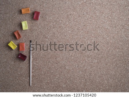 Warm colour paints with brush at beige background, flat lay, copy space