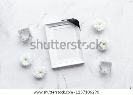 Death concept. Photo frame, mockup with black ribbon near flowers, candles on white stone background top view