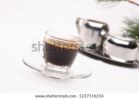 Hot black coffee in a clear glass on a white background with coffee beans.