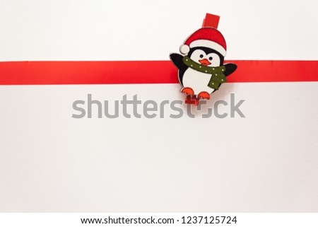 Penguin in a red hat and scarf on a white background. White background with red stripe. Background for new year greeting card. Template for post about Christmas
