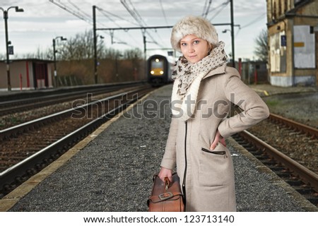 young woman in winter clothes waiting for her train