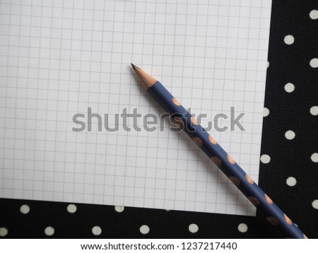 Polka dot pencil on polka dot tablecloth background with white grid writing paper space for text or messages e.g. Merry Christmas, New Year’s Resolutions, To Do Lists or Wish List 2019. (close up)