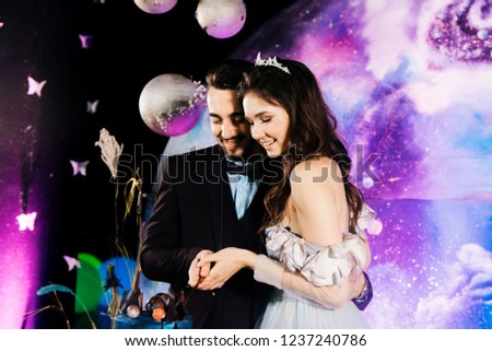 The bride and groom cut a space wedding cake decorated with chocolate and planets. The concept of festive desserts for the holiday