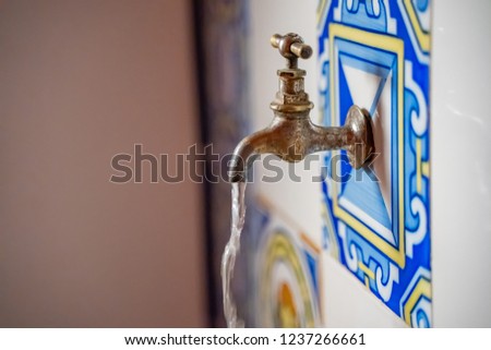 Close-up of wall fountain tap , colorful traditional water tap decorated with colorful shapes of mosaic. Traditional ornamental drinking fountain. Decorated fountain. 