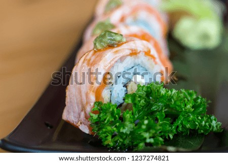 Salmon Avocado Roll With Wasabi Mayo Sauce and foie gras in black plate on wooden table with copy space.