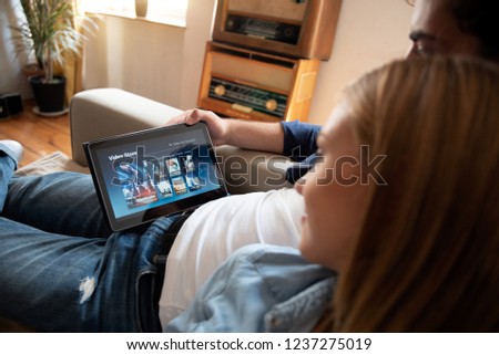 Couple using digital tablet for watching movie on VOD service. Video On Demand television internet stream multimedia concept
