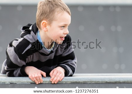 A little boy with ADHD, Autism, Aspergers Syndrome playing and posing for pictures on the Skateboard ramp and having fun at the park